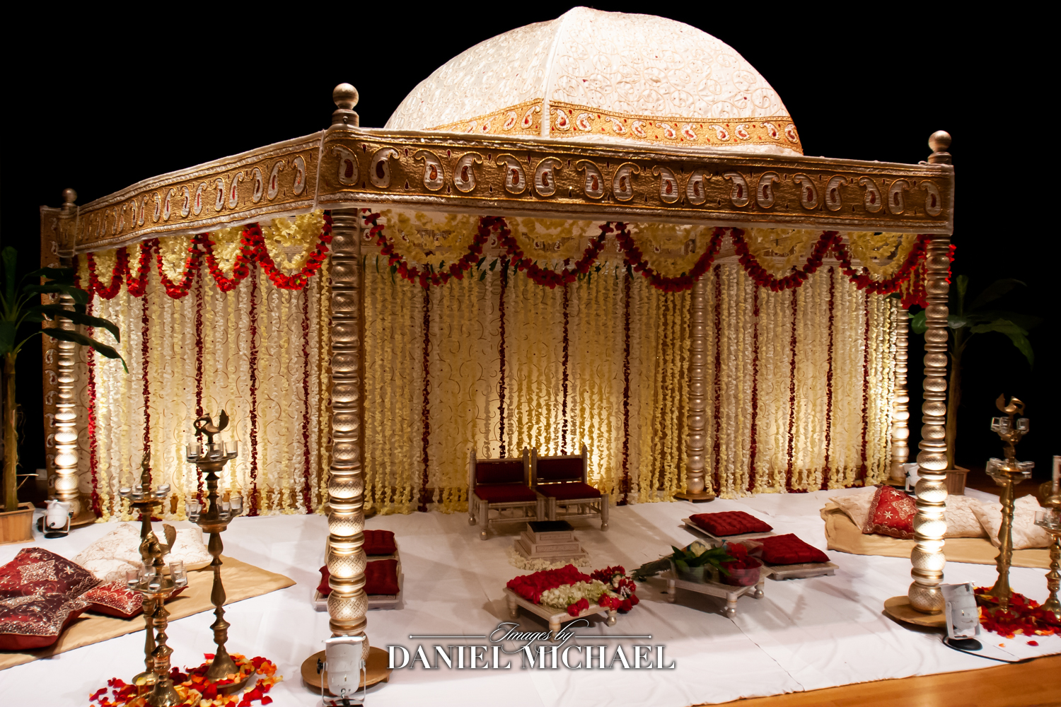 Elegant mandap adorned with red and gold fabrics at an Indian wedding